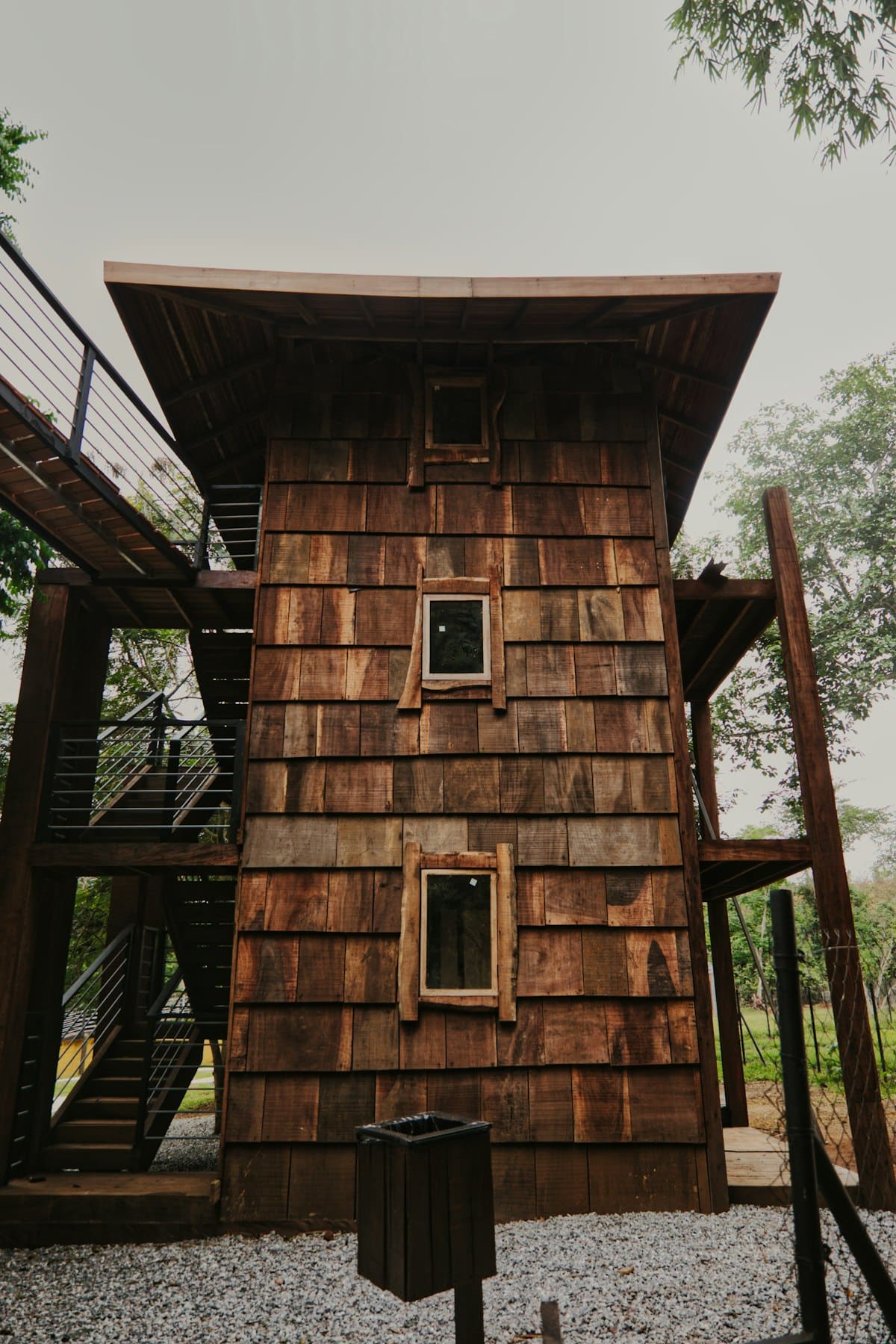 Wooden eco-home structure with outdoor stairs surrounded by tropical vegetation