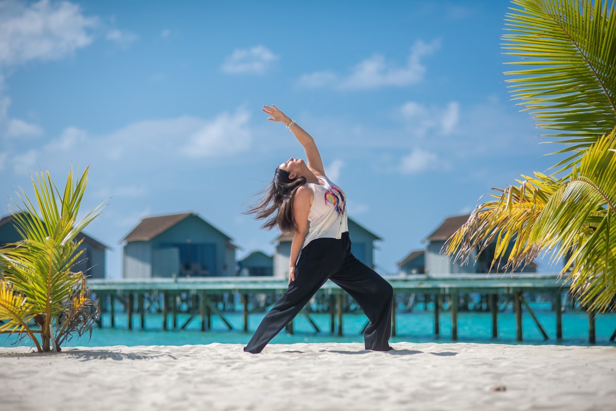 Woman practicing yoga on a sandy beach by the ocean