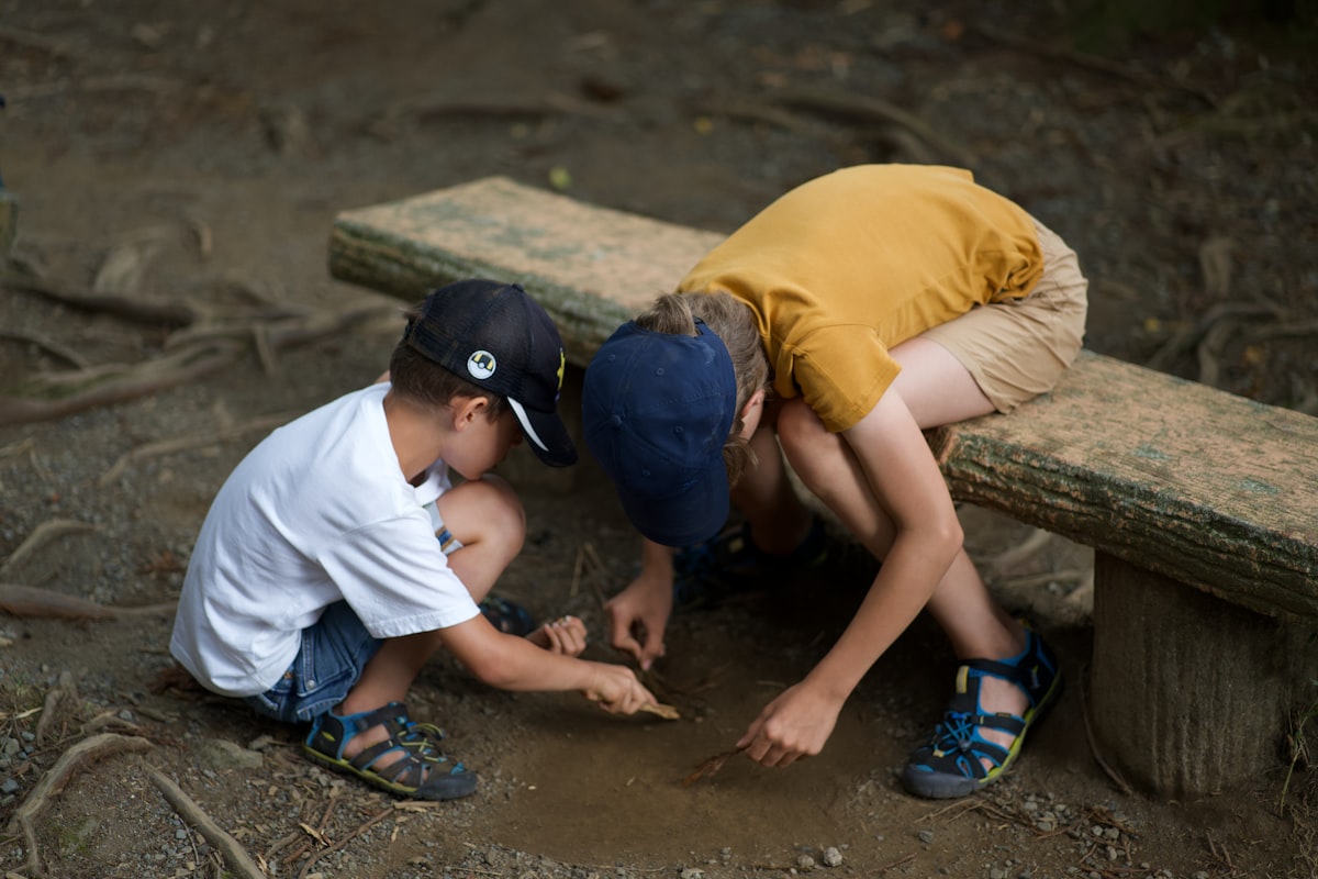 Children examining something together on the ground outdoors