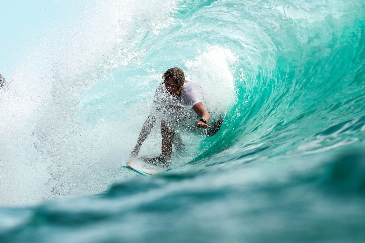 Surfer carrying a board along a long tropical beach on the Pacific coast of Mexico