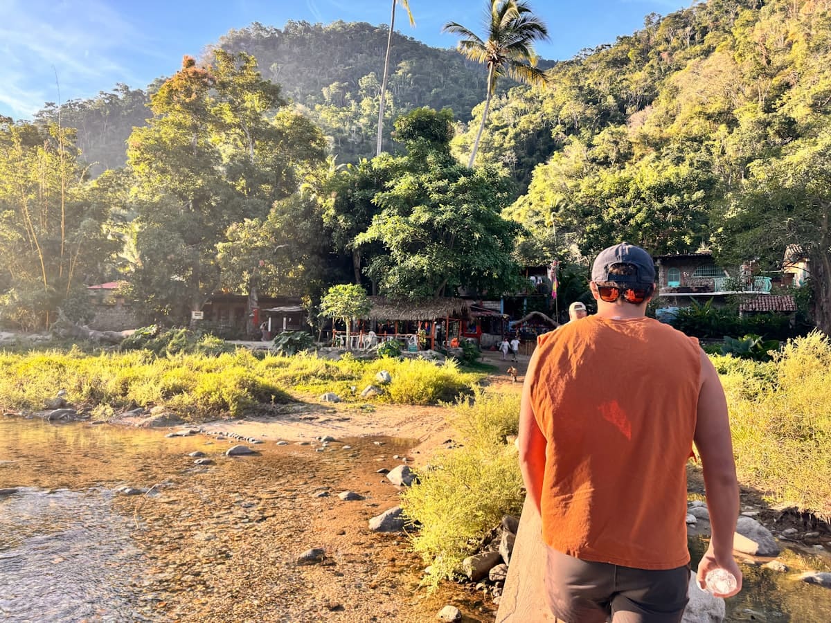 Person walking towards a jungle village at sunset