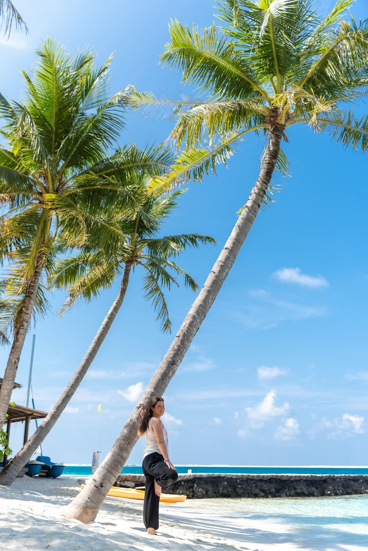 Woman leaning against a palm tree on a peaceful beach